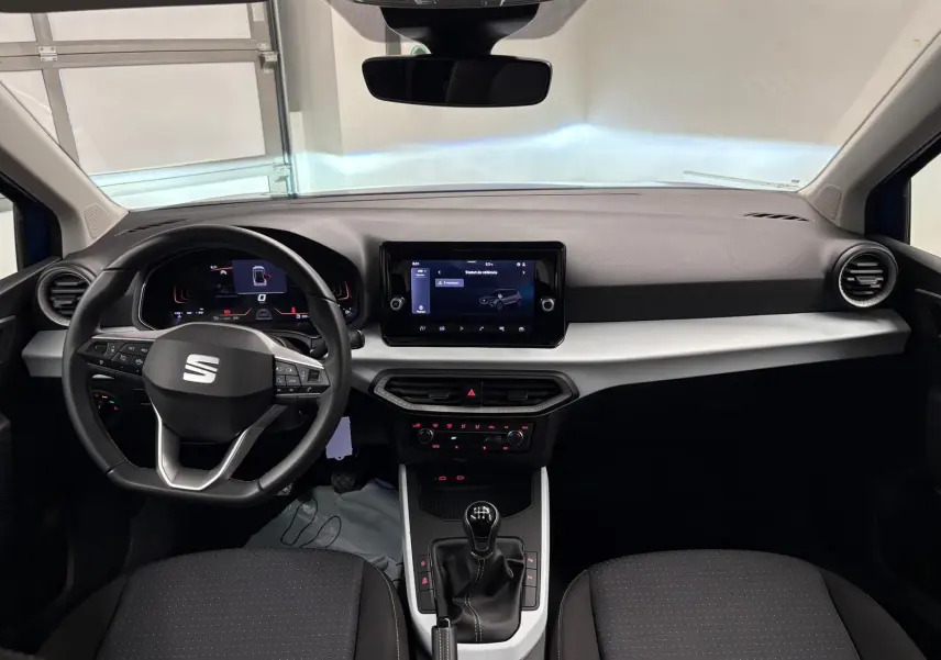 Vue intérieure frontale du tableau de bord et volant de la SEAT Arona 2025 avec boîte manuelle et écran tactile central.