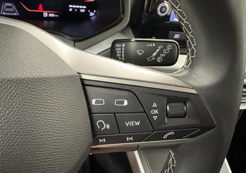 Gros plan sur les commandes au volant du SEAT Arona 2025, mettant en valeur les boutons multifonctions et la molette de réglage.