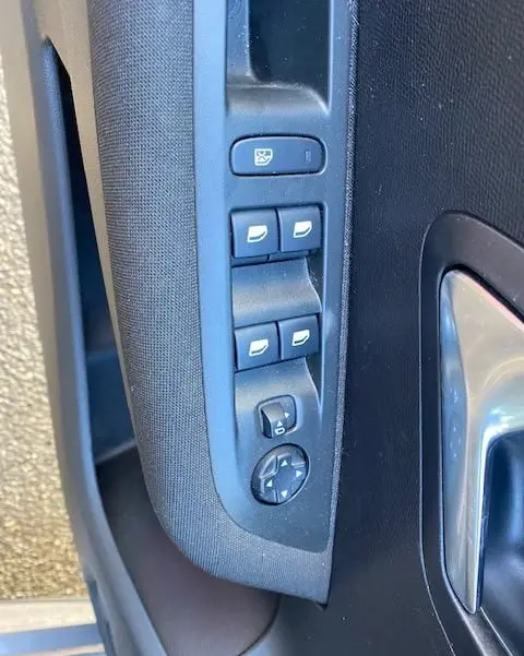Gros plan sur les commandes de lève-vitres et rétroviseurs sur la porte côté gauche d'une Peugeot 208 gris platinium.