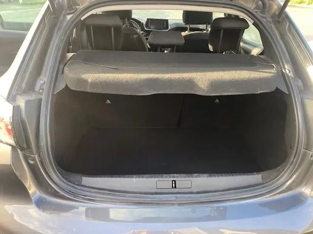 Coffre ouvert vu de l'arrière d'une Peugeot 208 gris platinium, montrant l'espace de chargement et l'intérieur arrière.