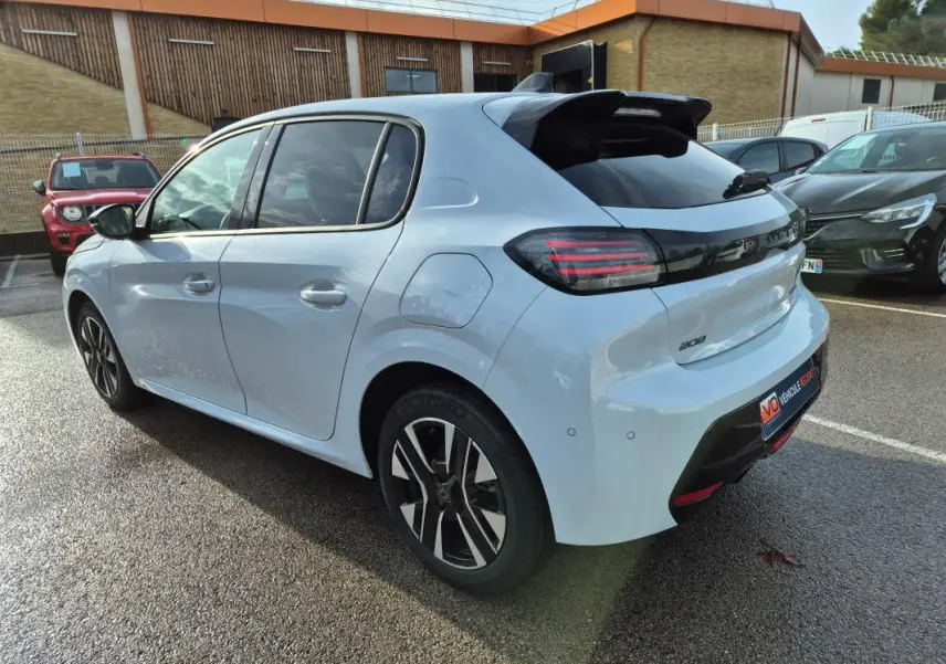 Vue 3/4 arrière droite d’une Peugeot 208 Hybrid 110 blanche avec jantes alliage 16 pouces et feux arrière LED noirs.