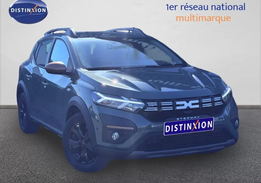 Vue 3/4 avant droite d'une Dacia Sandero Stepway 2025 en kaki lichen avec jantes noires et barres de toit.
