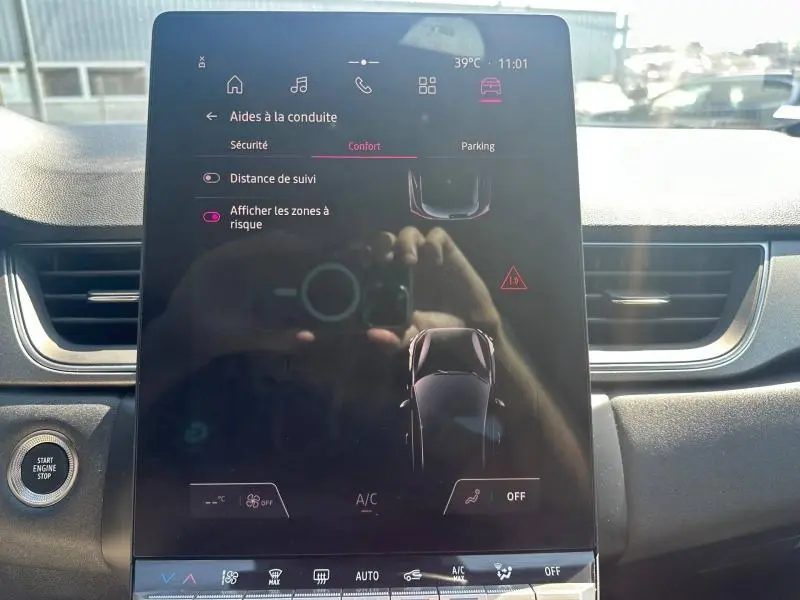 Écran tactile central du Renault Captur 2025 affichant les aides à la conduite, avec tableau de bord noir en arrière-plan.