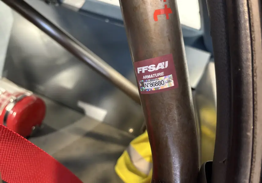 Extincteur rouge fixé au sol côté droit d'un Audi Coupé GT 1983 avec siège GT2i noir et arceau de sécurité.