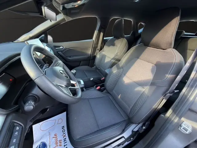 Vue intérieure côté conducteur du Renault Captur 2024, sièges tissu gris et volant en tissu avec boîte manuelle.