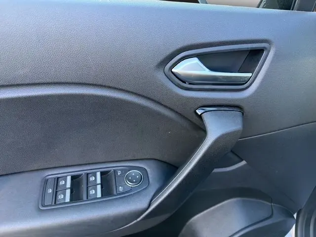Vue rapprochée de la porte avant gauche du Renault Captur gris Cassiopée avec commandes des vitres et poignée intérieure noire.