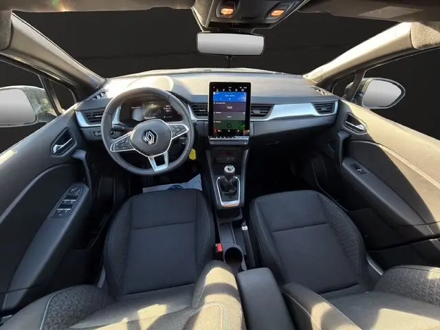 Vue intérieure avant du Renault Captur TCe 90 Evolution 2024, tableau de bord avec écran tactile vertical et sellerie tissu noire.