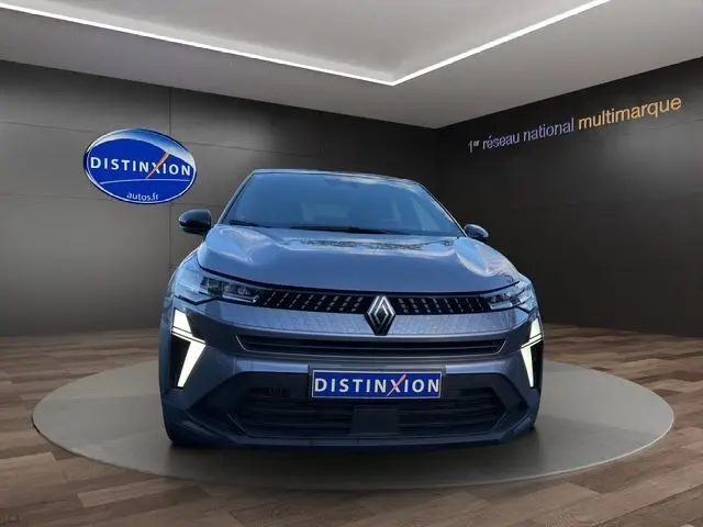 Vue de face du Renault Captur TCE 90 Evolution gris Cassiopée avec toit noir, feux LED allumés en showroom.