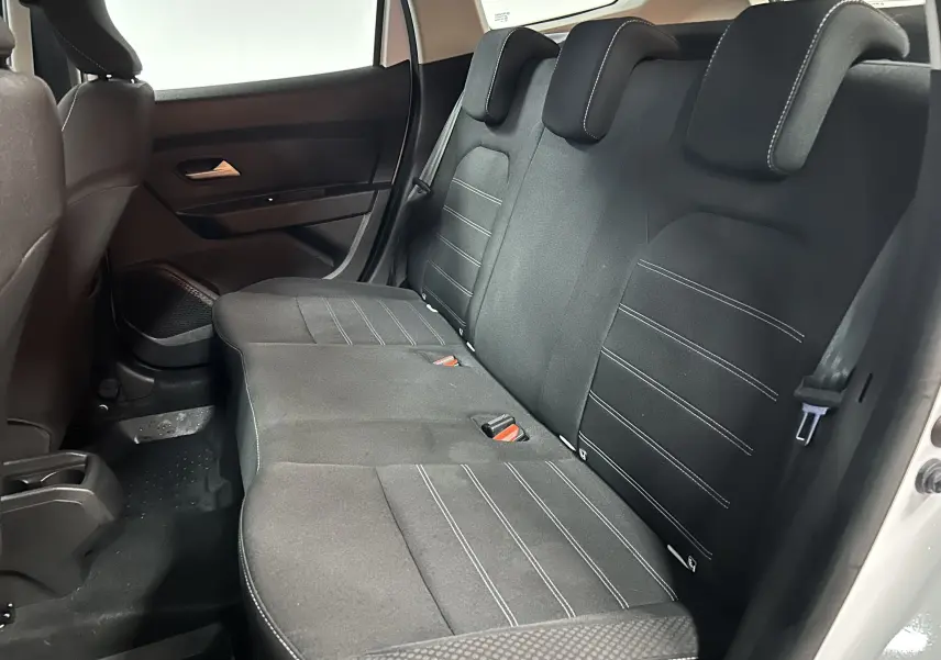 Vue intérieure côté droit des sièges arrière en tissu noir du Dacia Duster blanc 2025, version dCi 115 Expression 4x4.