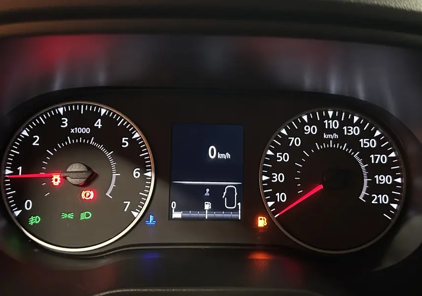 Tableau de bord du Dacia Duster blanc, affichage digital au centre avec vitesse à 0 km/h et voyants allumés.