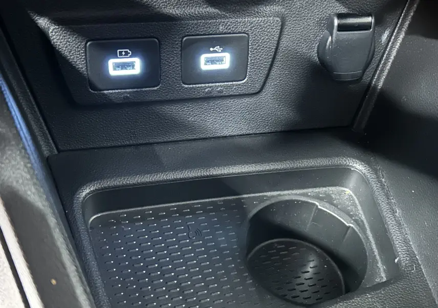 Gros plan intérieur sur la console centrale noire du Dacia Duster, avec deux ports USB éclairés et un emplacement porte-gobelet.