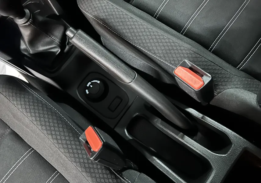Vue rapprochée de la console centrale du Dacia Duster 2025, montrant frein à main, bouton 4x4 et ceintures noires.