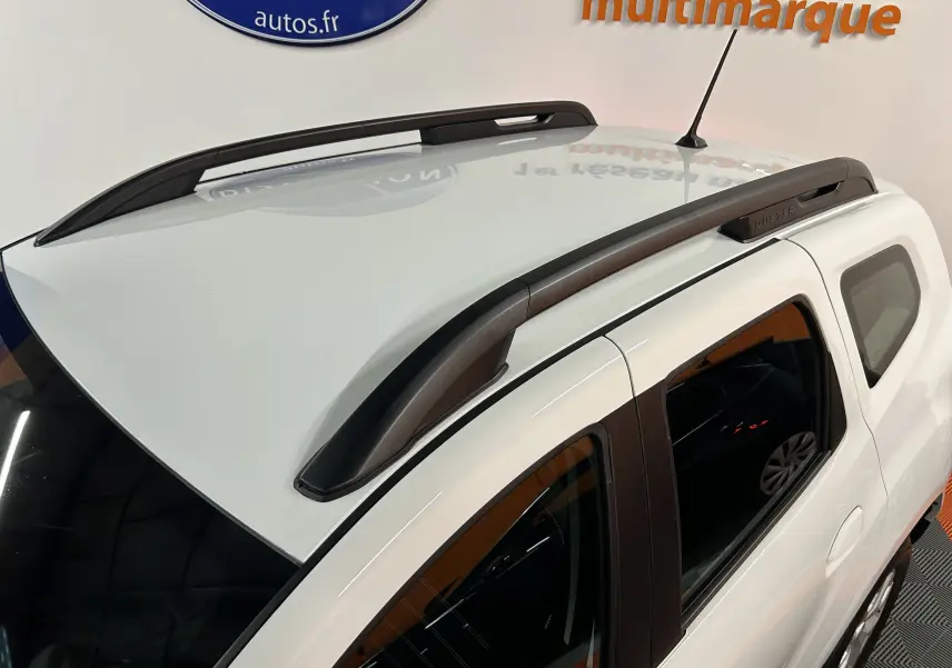 Vue en plongée du toit blanc du Dacia Duster 2025 avec barres de toit noires et antenne centrale.