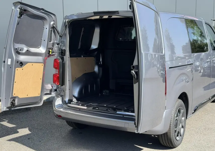 Vue arrière droite d'un Citroën Jumpy gris Artense avec portes battantes ouvertes dévoilant l'espace de chargement vide.