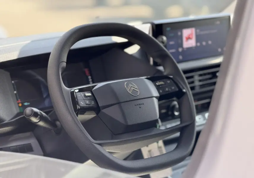 Vue rapprochée du volant Citroën Jumpy 2026 avec commandes intégrées et écran tactile en arrière-plan flou.