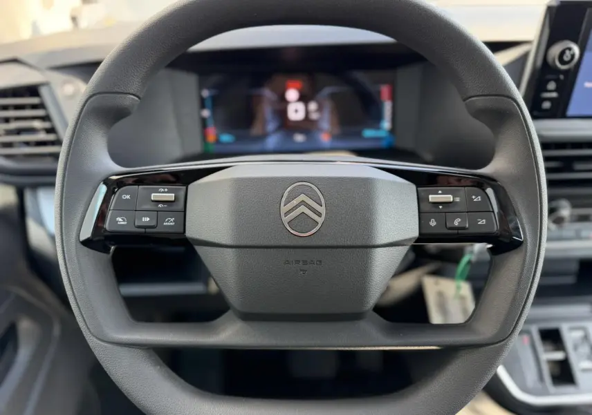 Vue rapprochée du volant noir de la Citroën Jumpy 2026 avec commandes intégrées et logo central argenté.