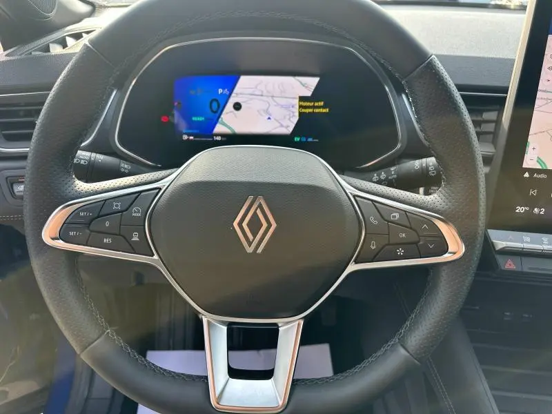 Vue rapprochée du volant cuir Renault Symbioz 2025 avec commandes intégrées et tableau de bord numérique affichant la navigation.