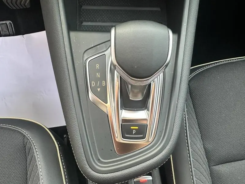 Vue rapprochée du levier de vitesses automatique noir et chrome du Renault Symbioz 2025, entouré de sellerie noire avec surpiqûres claires.