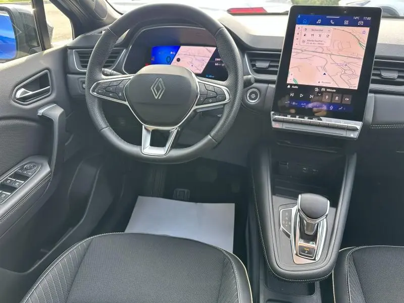 Vue intérieure avant du tableau de bord du Renault Symbioz 2025 avec volant cuir, écran tactile vertical et levier de vitesse moderne.