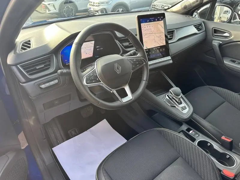 Vue intérieure côté conducteur de la Renault Symbioz 2025 avec volant cuir, écran tactile vertical et sièges noirs.