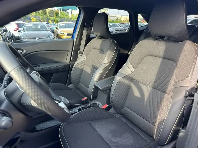 Vue intérieure côté conducteur du Renault Symbioz 2025, sièges en tissu noir avec surpiqûres contrastées et volant cuir.