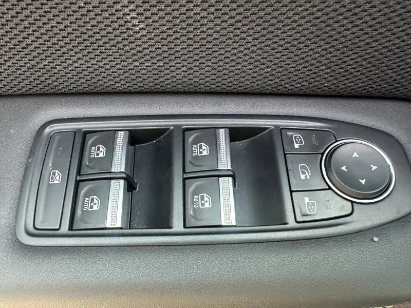 Gros plan sur les commandes de lève-vitres et rétroviseurs électriques côté gauche intérieur du Renault Symbioz rouge Flamme.