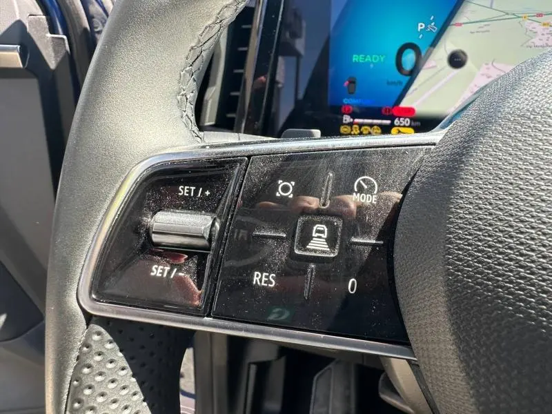 Gros plan sur les commandes au volant du Renault Austral 2025, affichage numérique bleu et carte GPS en arrière-plan.