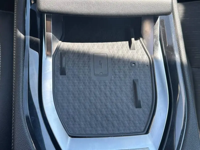 Gros plan sur le chargeur sans fil noir intégré à la console centrale du Renault Austral 2025 bleu Iron.