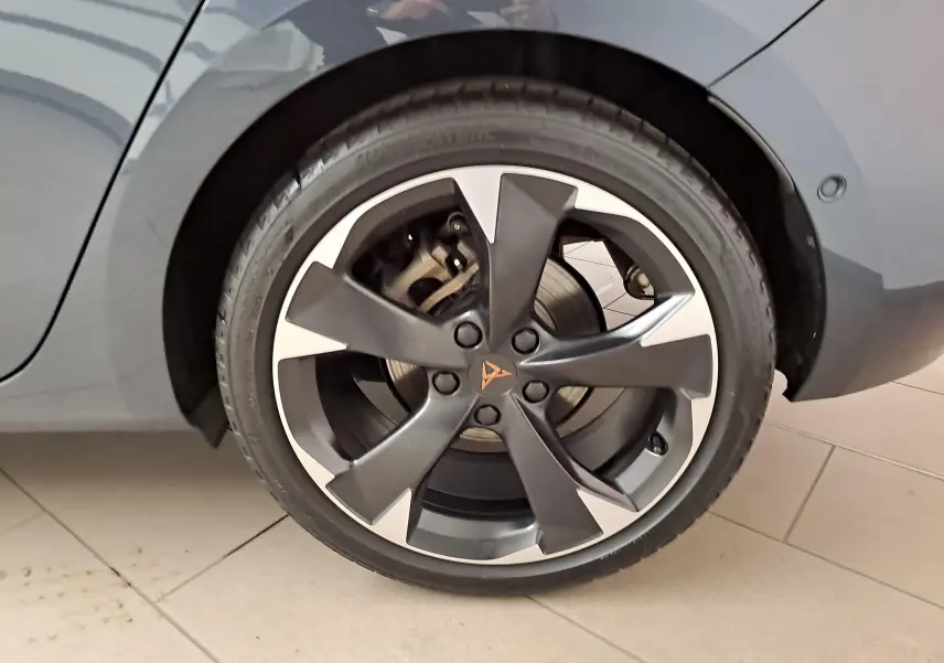 Gros plan sur la roue arrière droite d'une CUPRA Leon 2023 gris magnétique avec jante alliage bicolore distinctive.