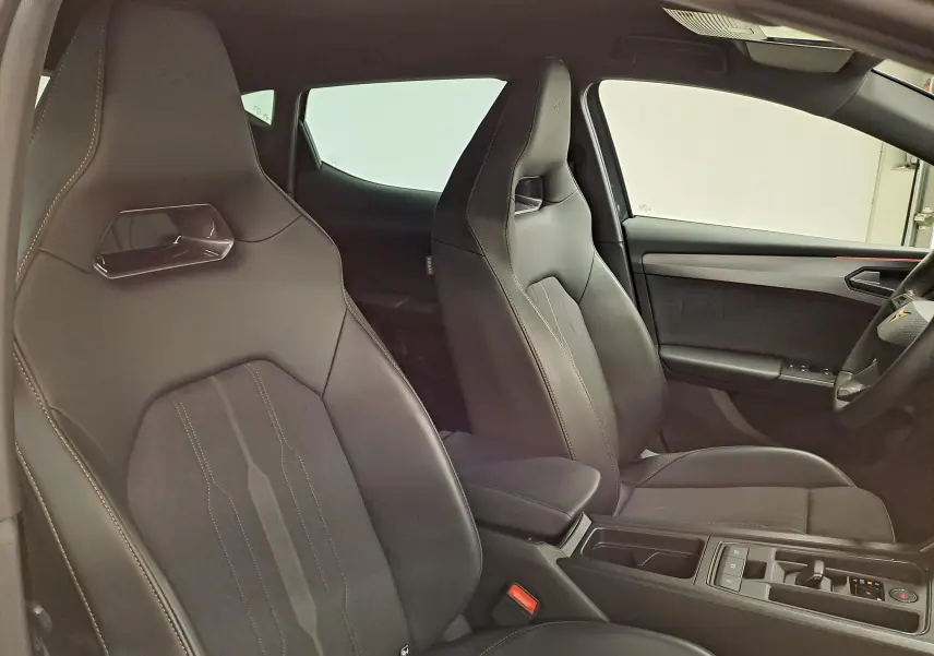 Intérieur de la CUPRA Leon 2023, vue latérale des sièges avant sport en cuir noir avec surpiqûres contrastées.