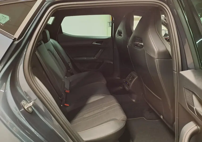 Vue intérieure côté gauche des sièges arrière en cuir noir du CUPRA Leon 2023 gris magnétique, avec aérations centrales visibles.