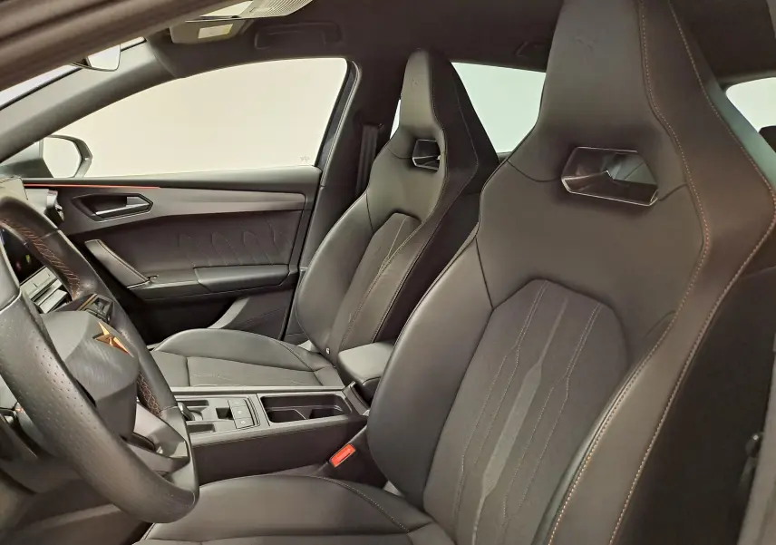 Vue intérieure côté conducteur de la CUPRA Leon 1.5 TSI 150 DS7 V 2023, sièges sport noirs avec surpiqûres marron.