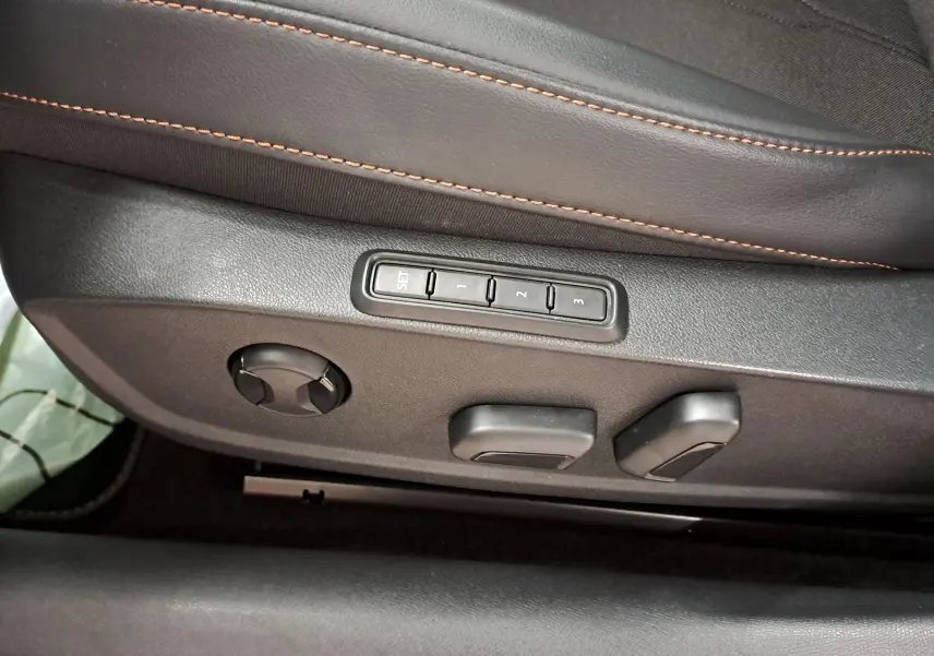 Détail des commandes de réglage électrique du siège conducteur avec surpiqûres orange sur cuir noir dans une CUPRA Leon 2023.