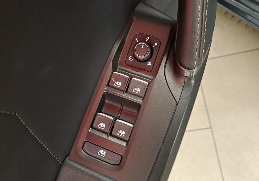 Gros plan sur les commandes de lève-vitres et réglage des rétroviseurs côté conducteur d'une CUPRA Leon gris magnétique 2023.