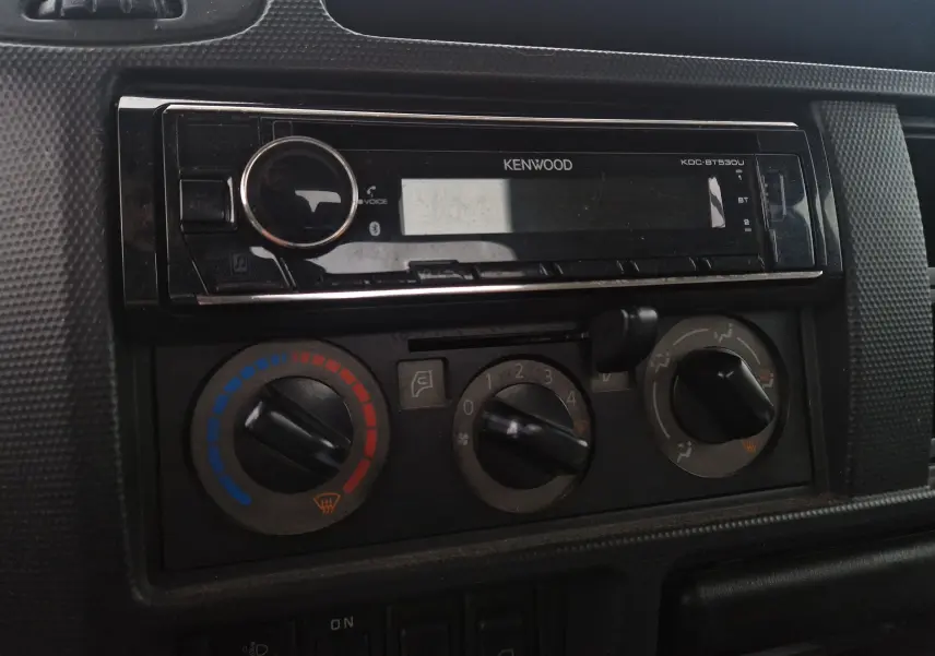 Gros plan sur la console centrale intérieure du Nissan Cabstar blanc, avec autoradio Kenwood et commandes de climatisation.