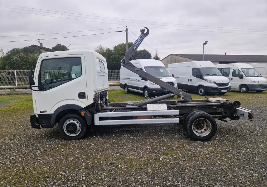 Vue de profil côté gauche d'un Nissan Cabstar blanc 2010 avec châssis cabine et bras polybenne levé.