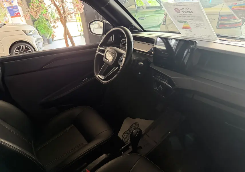 Vue intérieure côté conducteur du tableau de bord et volant du Ligier JS50 Elite Revo D+ gris graphite avec écran tactile central.