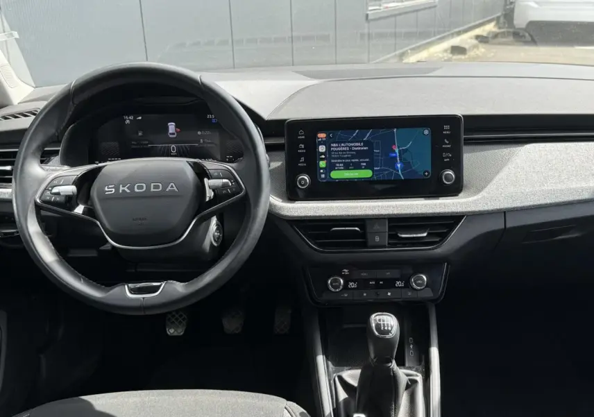 Vue intérieure frontale du tableau de bord et volant cuir noir de la Skoda Scala TSI 116, avec écran tactile et levier de vitesses manuel.