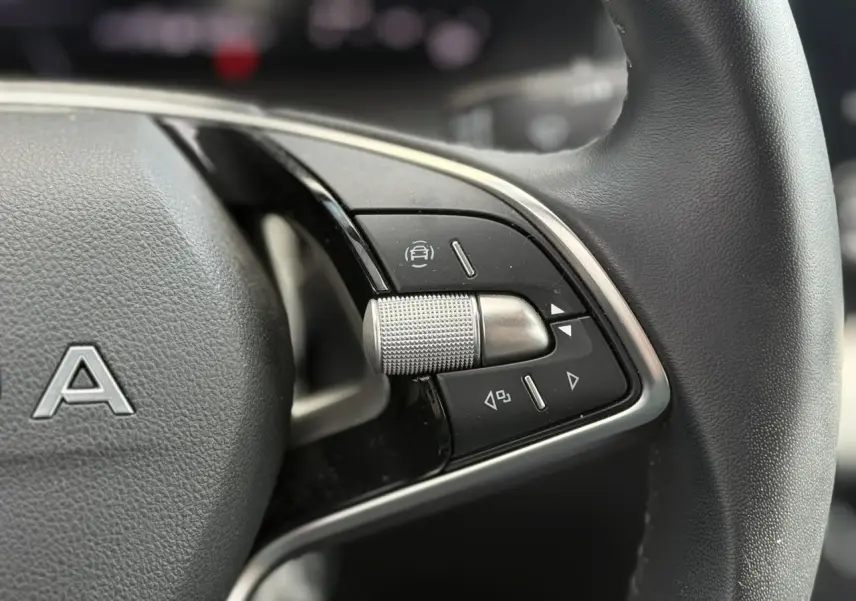 Gros plan sur les commandes à droite du volant en cuir noir de la Skoda Scala TSI 116 gris graphite.