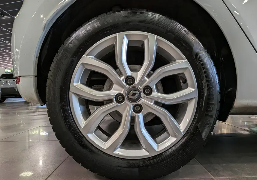 Gros plan sur la roue avant droite d'une Renault Clio IV blanche, mettant en valeur la jante alliage 16 pouces et le pneu Continental.