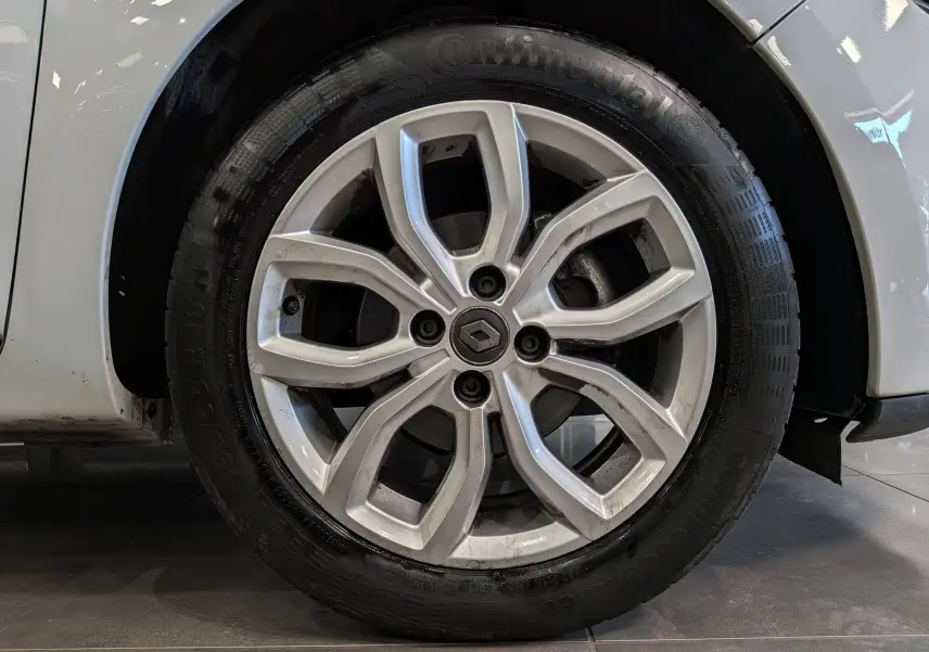 Gros plan sur la jante alliage 16 pouces de la Renault Clio IV blanc glacier, avec logo Renault au centre.