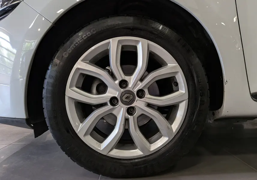 Gros plan sur la roue avant droite de la Renault Clio IV blanche Glacier avec jante alliage 16 pouces et logo Renault central.