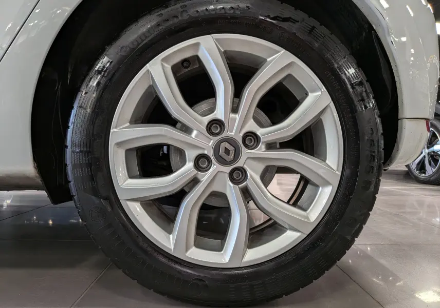 Gros plan sur la jante alliage argentée de la Renault Clio IV Blanc Glacier, avec logo Renault au centre.