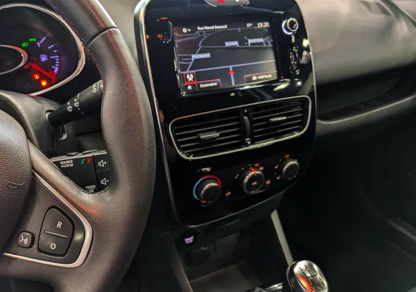 Vue intérieure côté conducteur de la Renault Clio IV TCe 75 blanche, avec tableau de bord noir et écran tactile central.