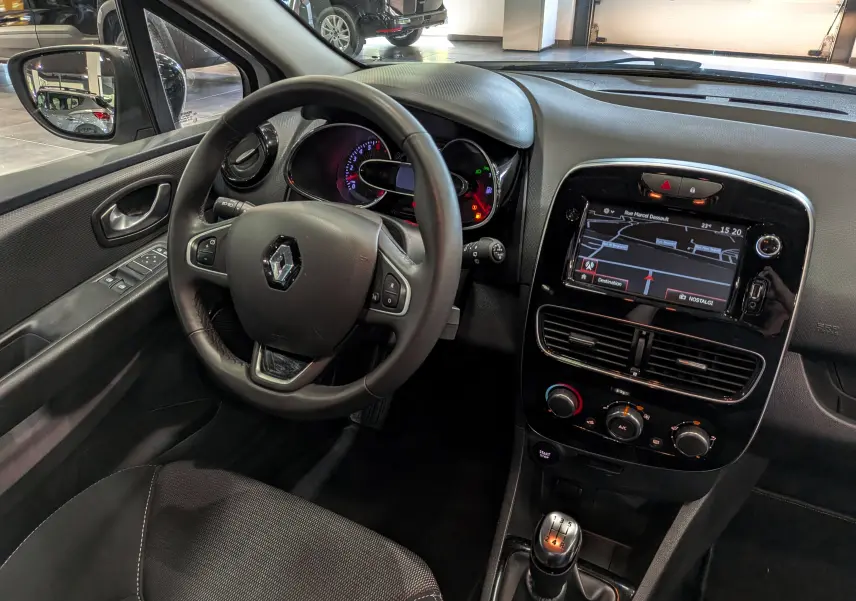 Vue intérieure côté conducteur de la Renault Clio IV TCe 75 blanche, avec tableau de bord et écran tactile GPS.