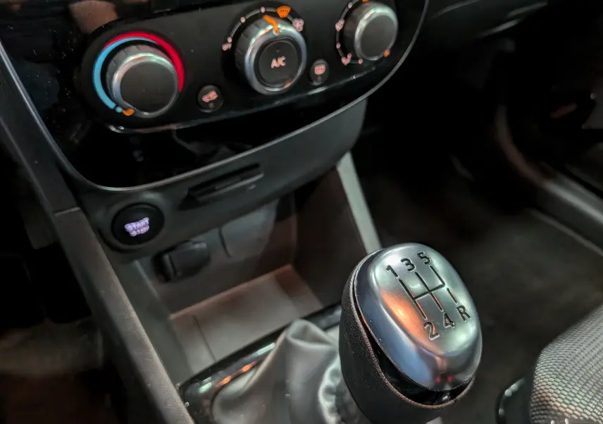 Gros plan sur la commande de boîte manuelle et les réglages de climatisation d’une Renault Clio IV Blanc Glacier de 2020.