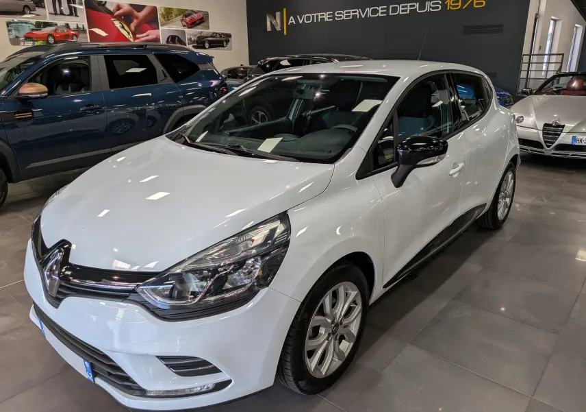 Renault Clio IV TCe 75 blanc Glacier vue 3/4 avant droit en showroom avec rétroviseurs noirs brillants.