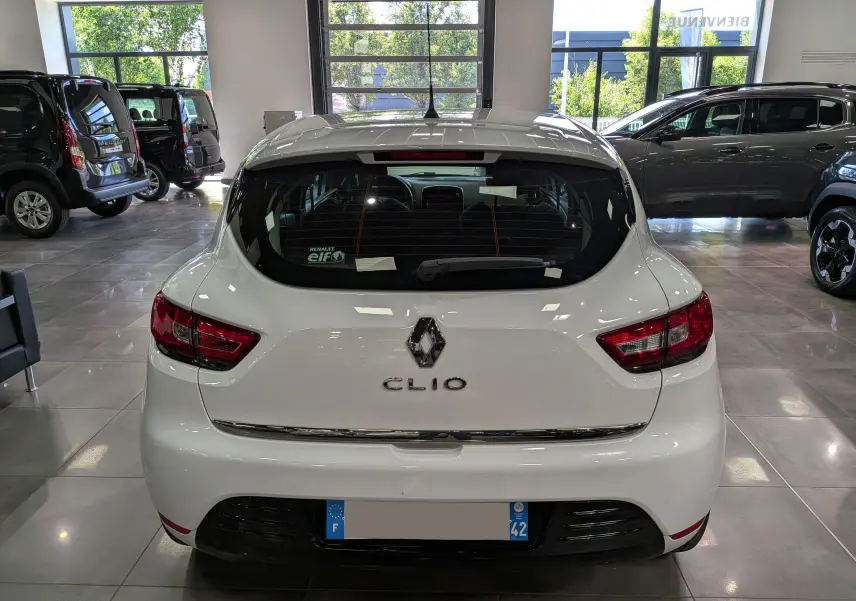 Vue arrière d'une Renault Clio IV TCe 75 blanche Glacier, en intérieur, avec logo et feux arrière visibles.