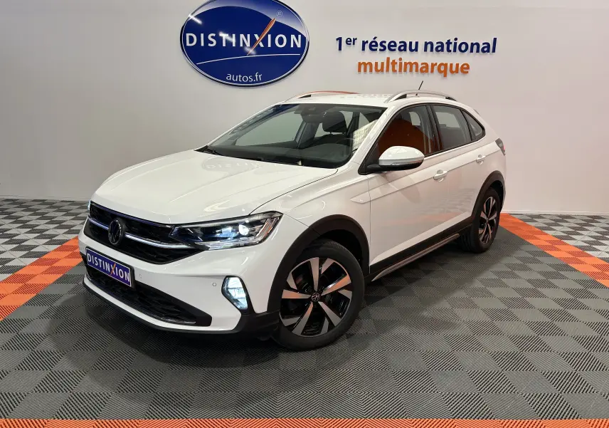 Volkswagen Taigo blanc pur en 3/4 avant droit, avec jantes noires et phares LED allumés dans un showroom.