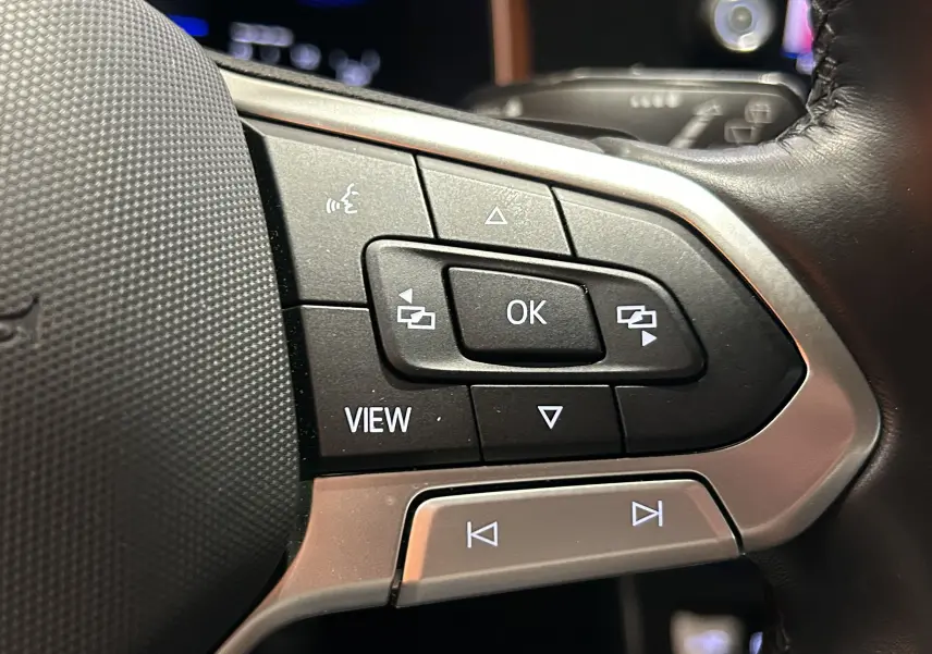 Gros plan sur les commandes multifonctions au volant en cuir noir du Volkswagen Taigo blanc Pur 2022.